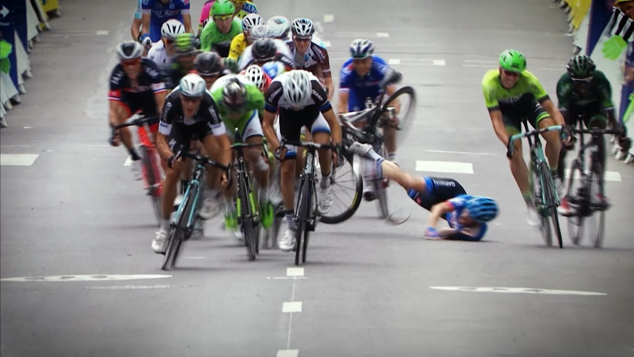 Cyclists in a race; one has fallen on the road while others continue riding ahead.