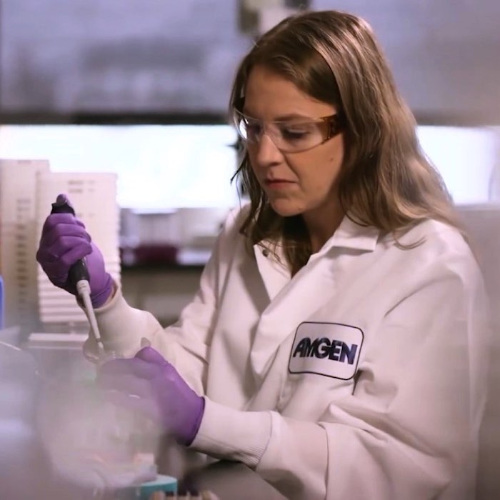 Scientist in a lab coat using a pipette, working in a laboratory setting.