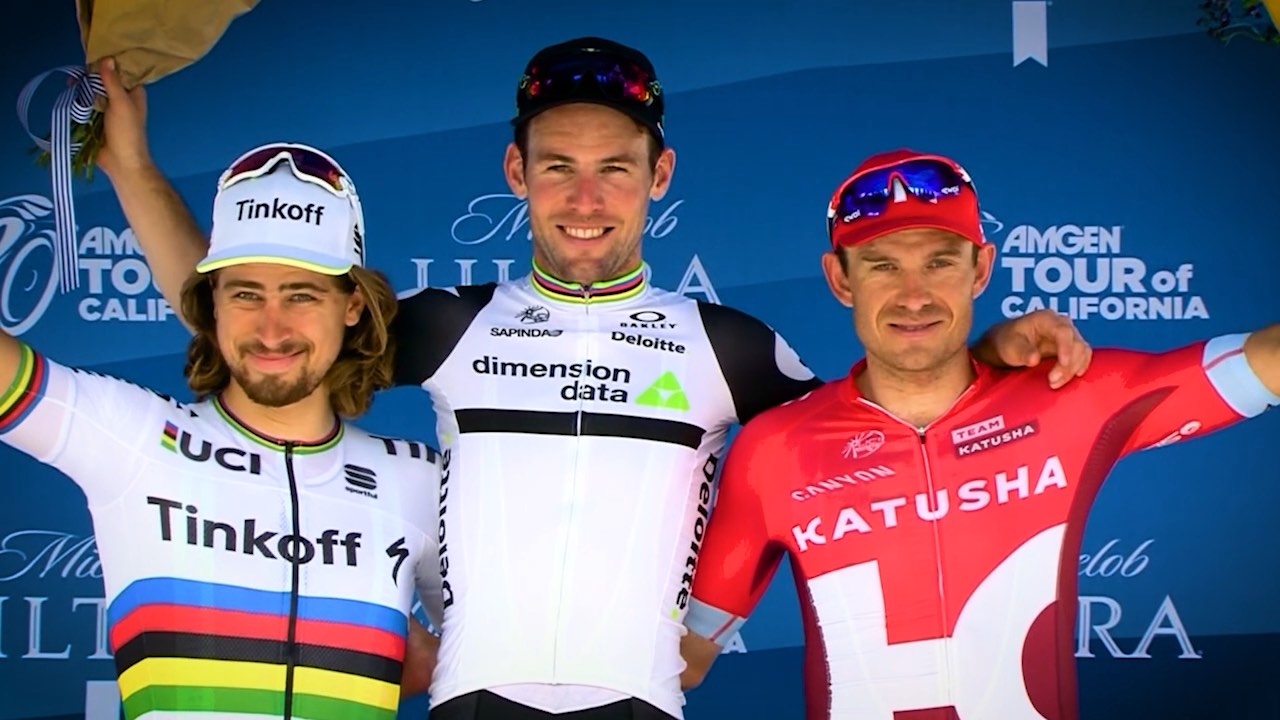 Three cyclists in racing jerseys stand on a podium, smiling and holding their arms around each other.
