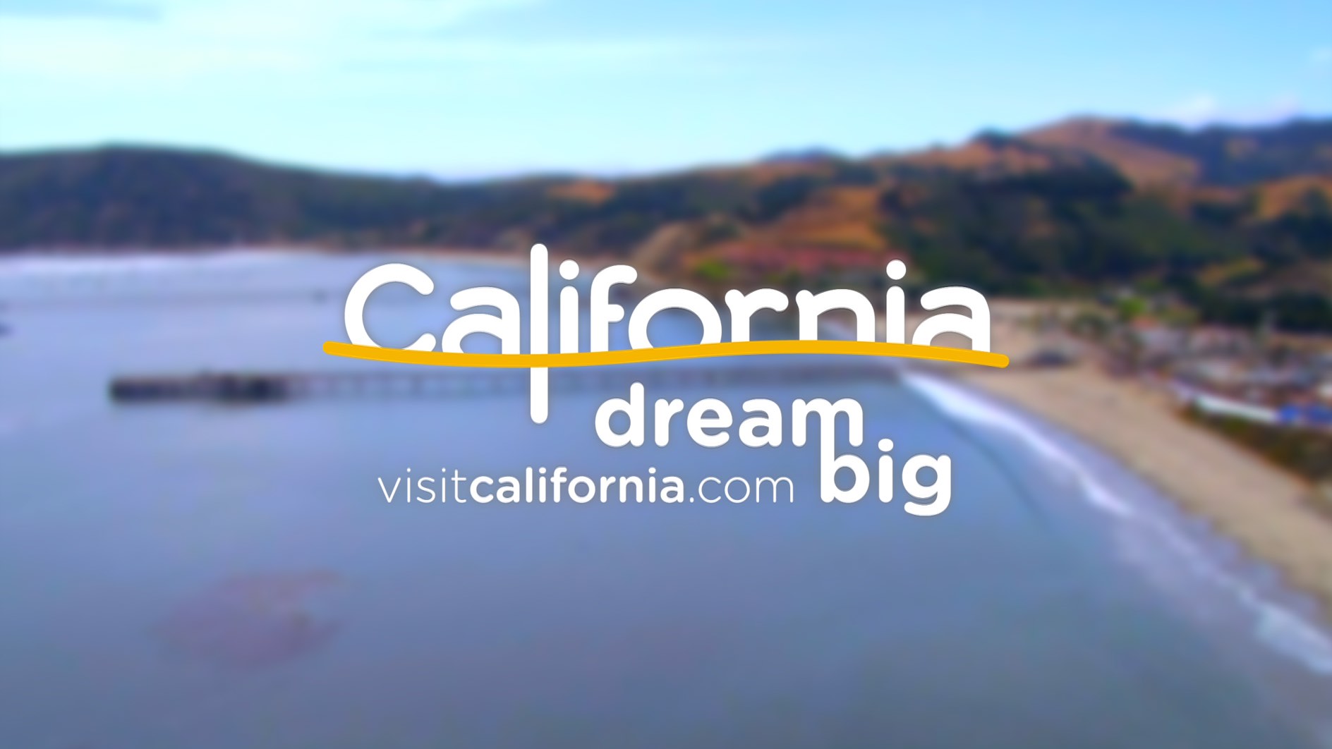 Blurred coastal view with hills, pier, and beach. Text reads "California dream big visitcalifornia.com.