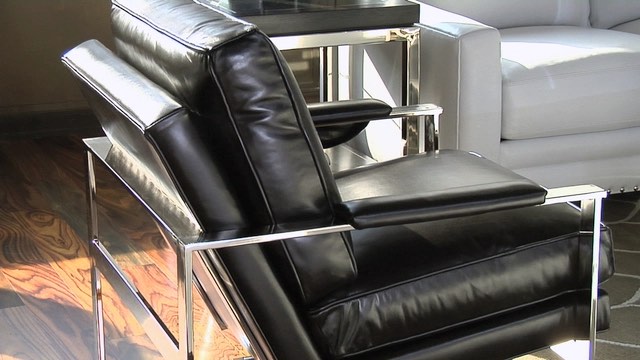 A modern black leather armchair with sleek metal frame beside a white sofa and a small table.