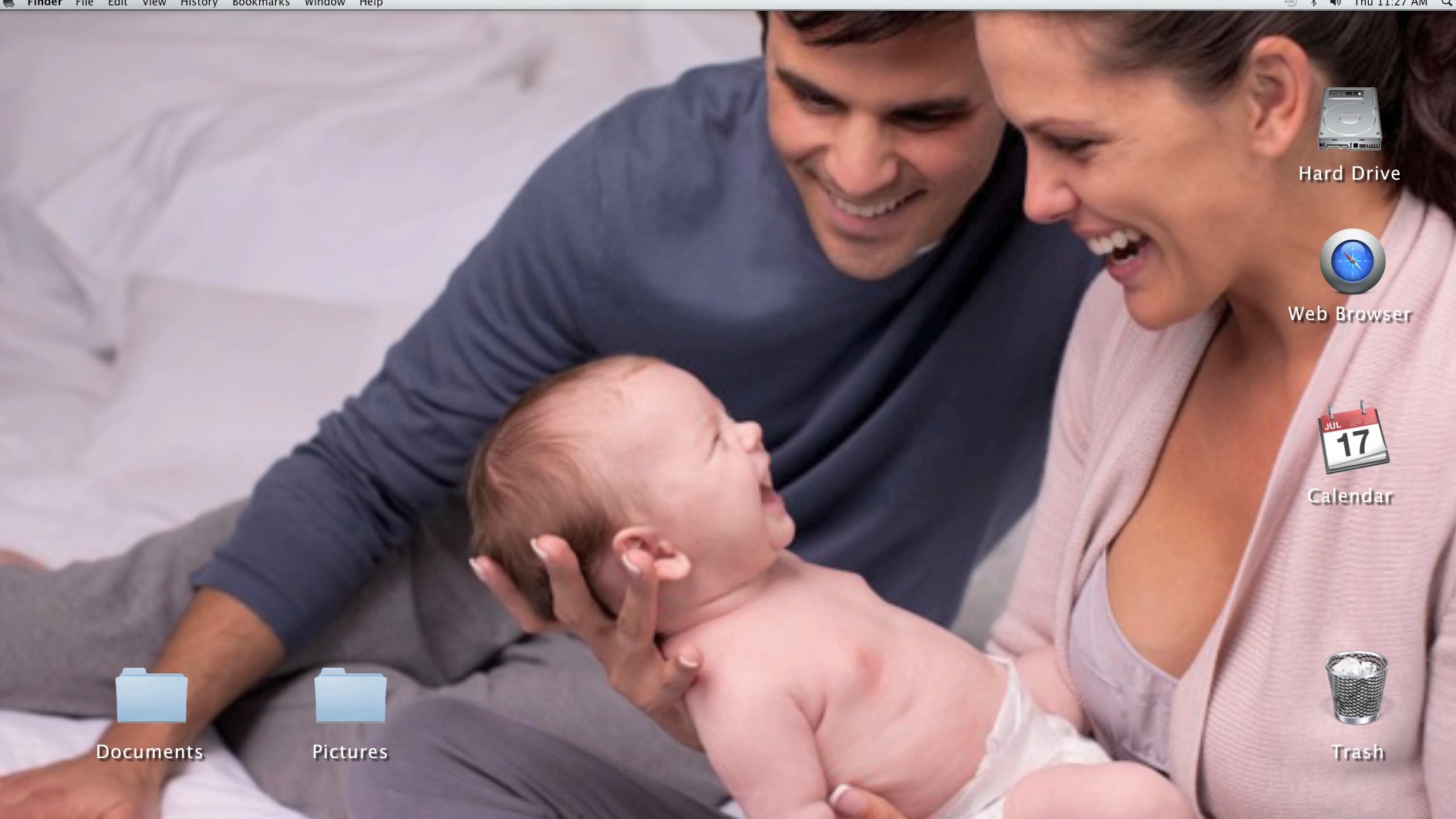 Smiling couple sitting on a bed holding a laughing baby, with computer icons visible on the right side.