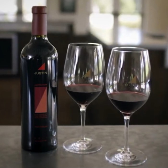 Wine bottle and two filled wine glasses on a countertop, with a blurred background.