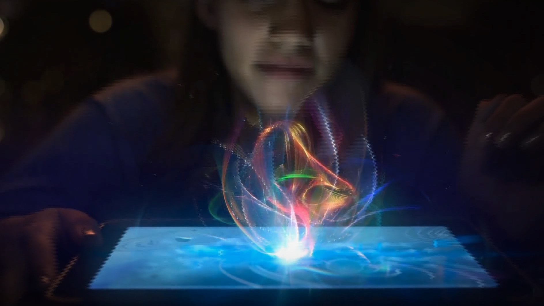 Person looking at a tablet displaying colorful, glowing abstract light patterns.