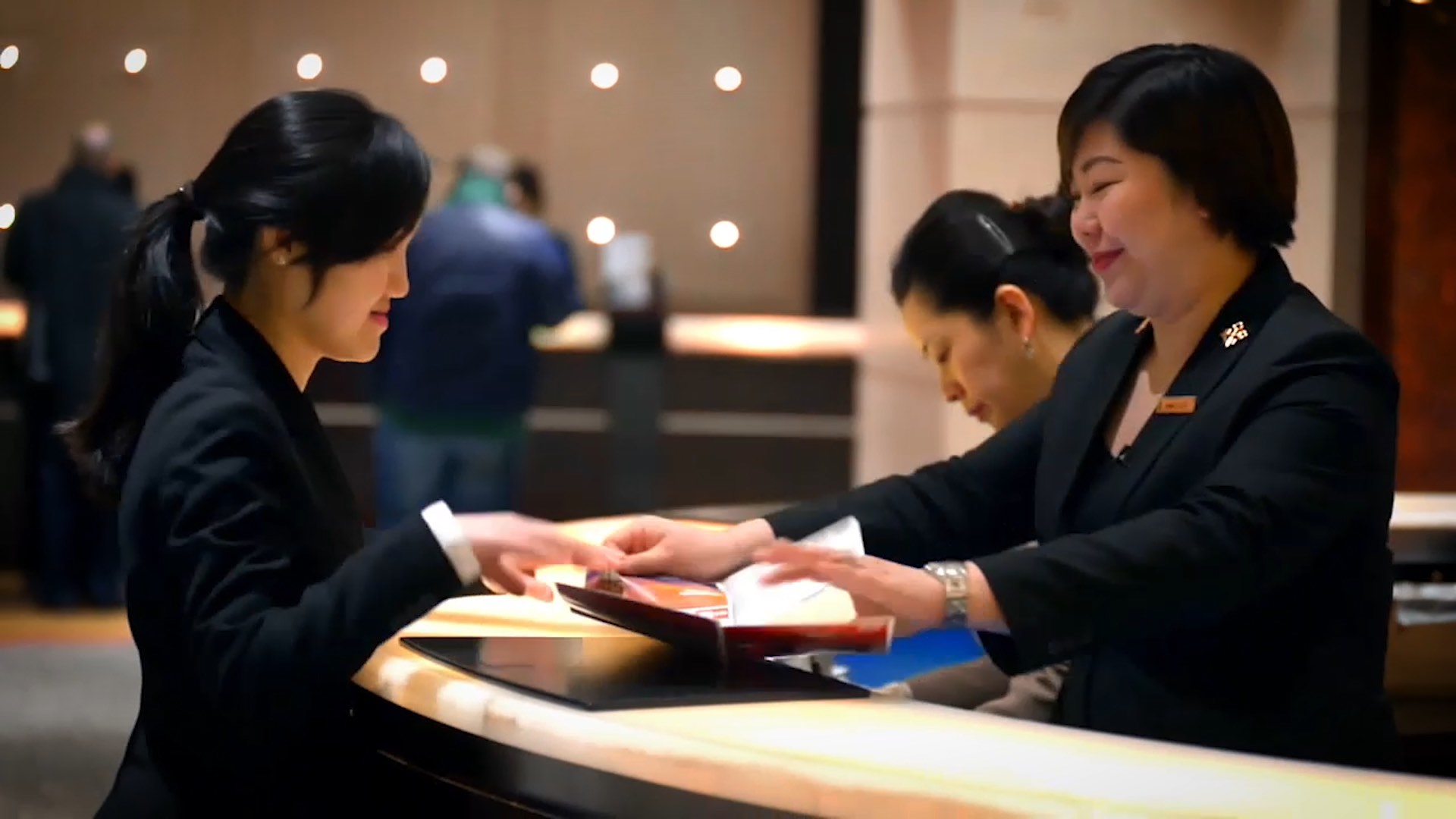 Hotel staff assisting a guest at a reception desk, exchanging documents with a friendly demeanor.
