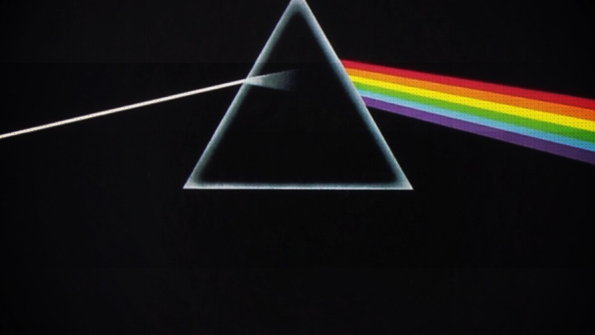 A prism on a black background dispersing white light into a spectrum of colors.