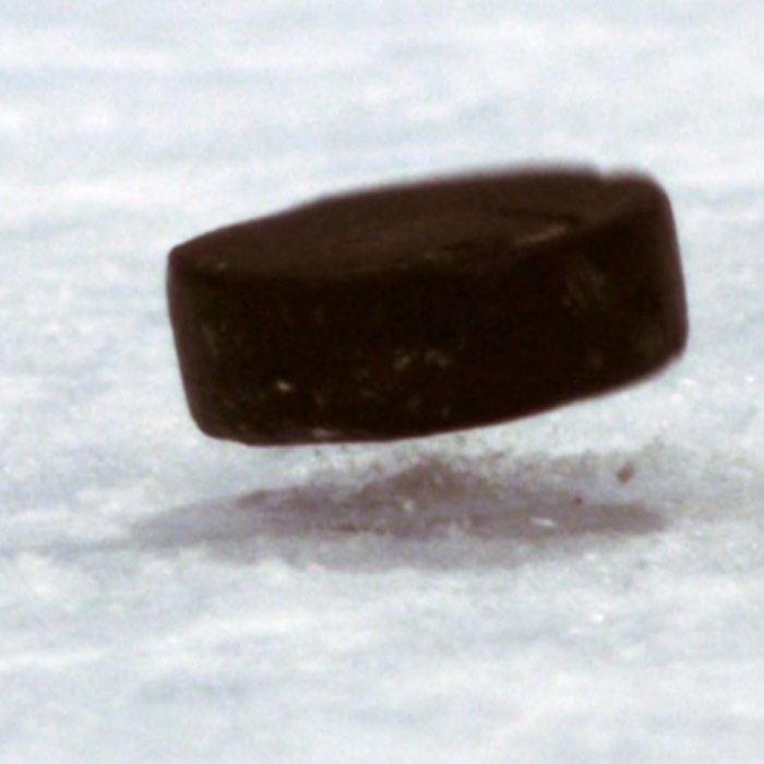 Close-up of a hockey puck mid-air on an ice rink.