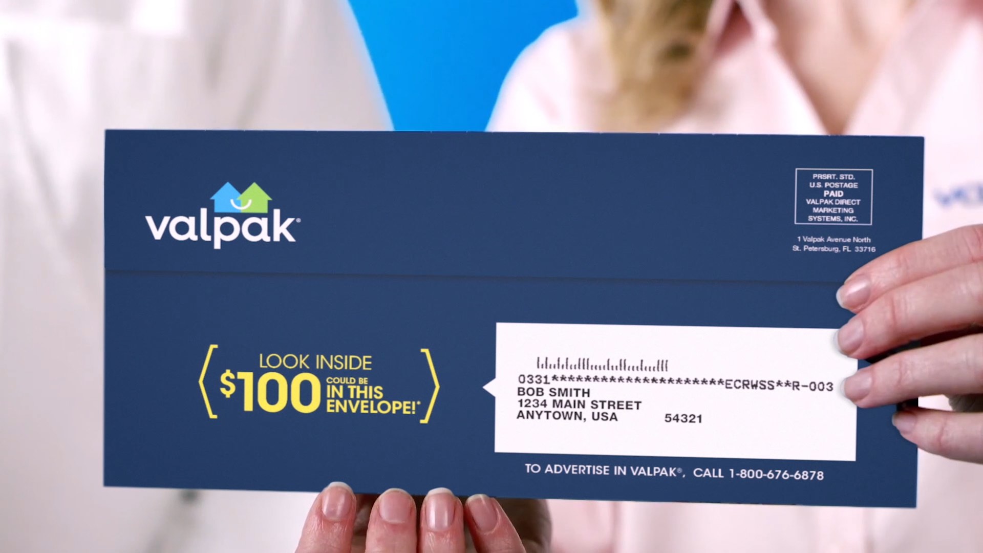 Close-up of two people holding a Valpak envelope advertising a chance to win $100.