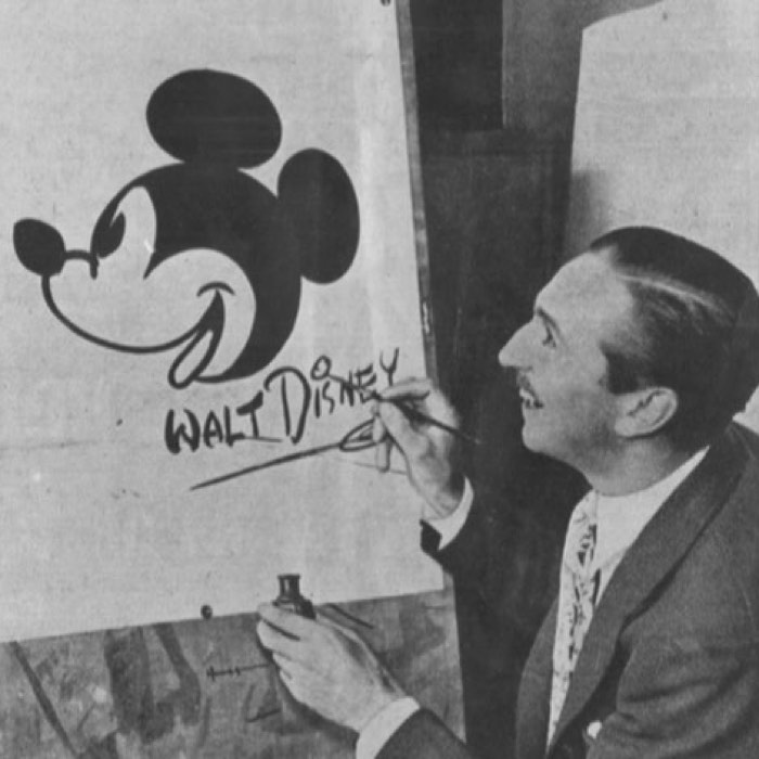 A person drawing a classic Mickey Mouse image on a board, with "Walt Disney" written below.