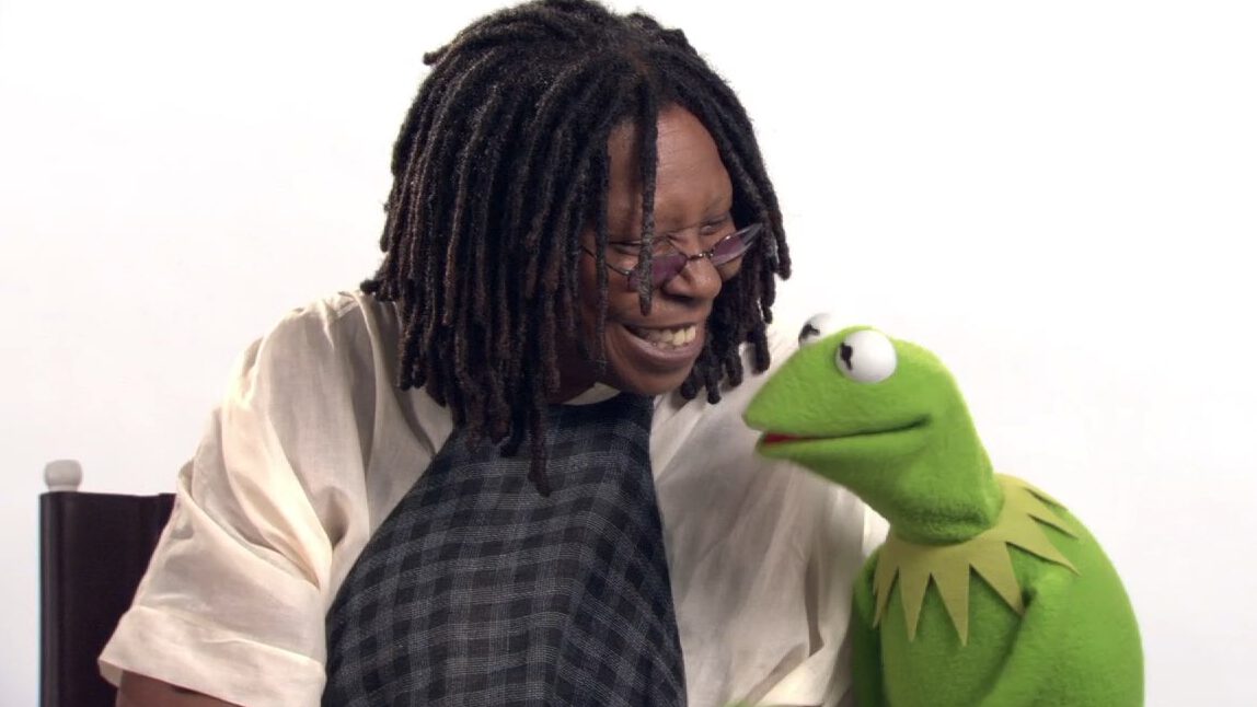 Person smiling at Kermit the Frog against a white background.